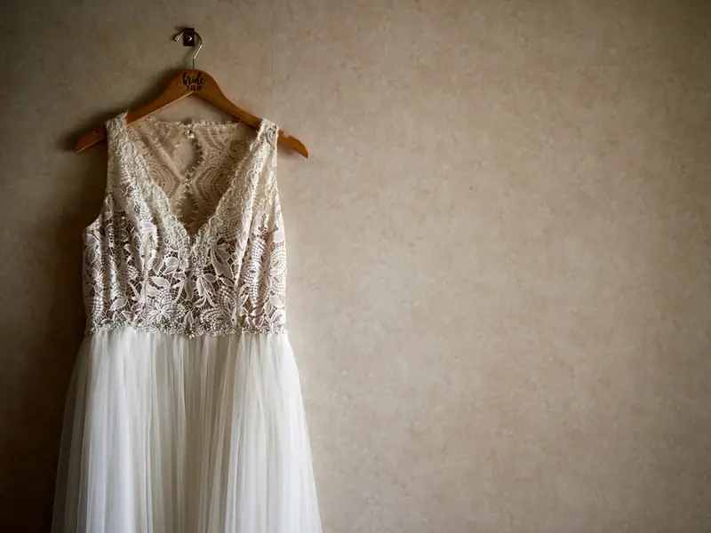 Abito da sposa in pizzo appeso a una gruccia di legno