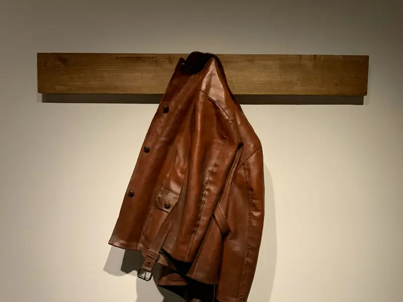 Giacca di pelle marrone appesa a un gancio di legno
