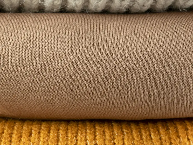 Capi in maglia piegati, nei toni del bianco, del beige e dell'ocra